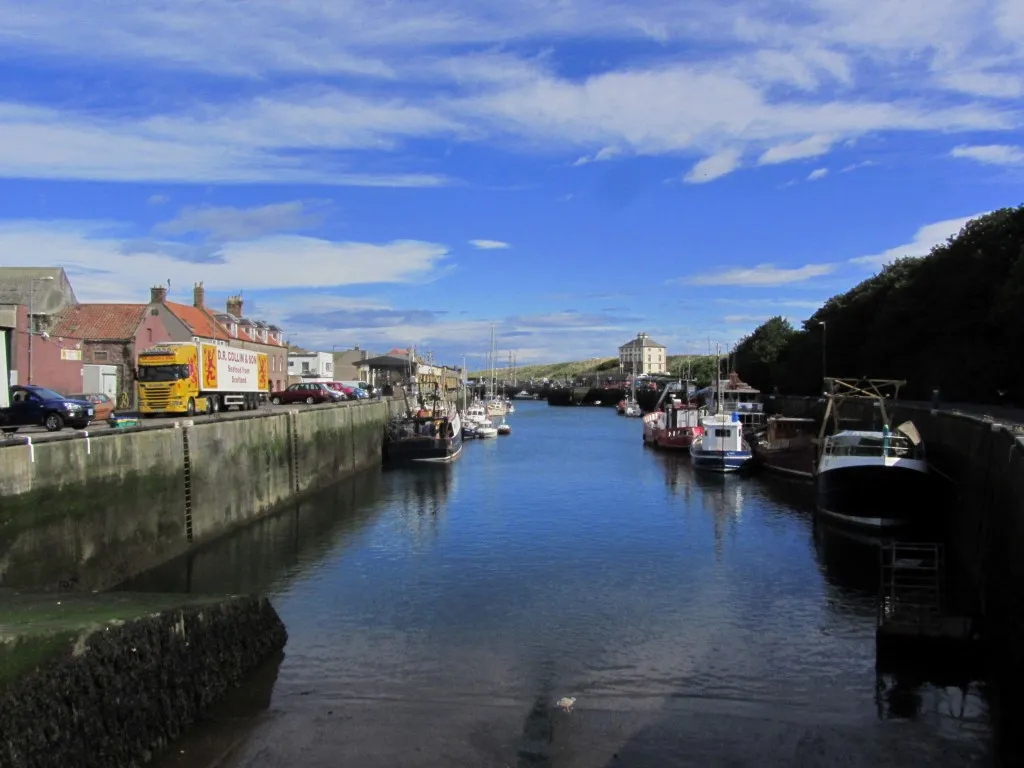 Eyemouth Harbour on a still fine summer's morning. In the distance is Gunsgreen House famed for its smuggling history.
